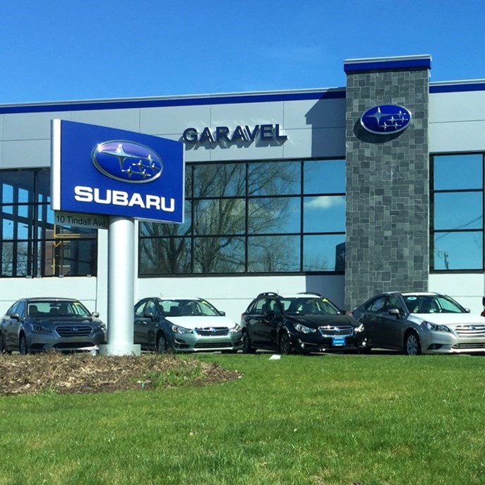 Front of Subaru dealership. I nview is signage and a glass and brick facade with cars parked out front.